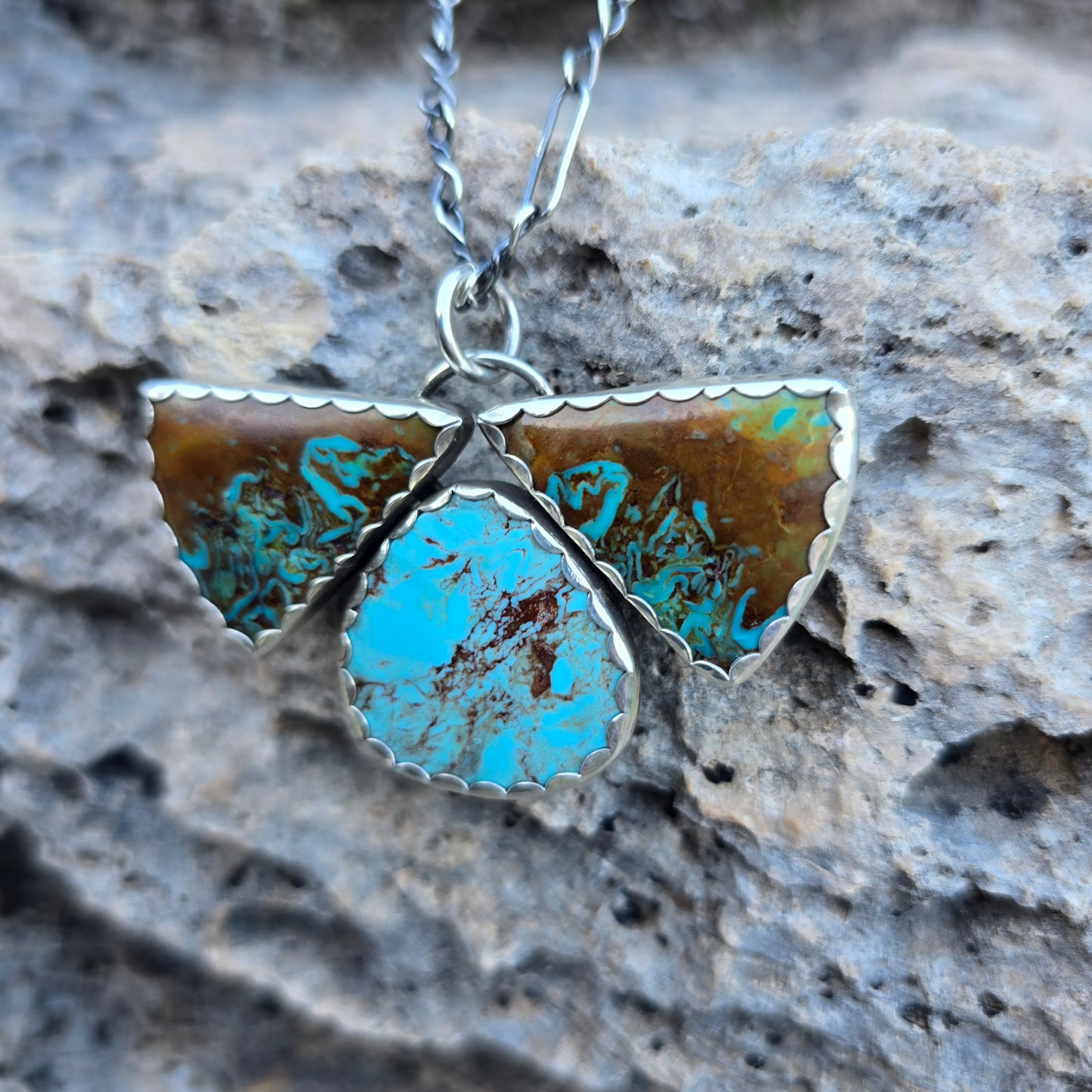 Three stone Patagonia turquoise pendant measuring approximately 1.75 inches, featuring two triangular stones and one oval stone in blue and brown tones with a scalloped silver bezel.