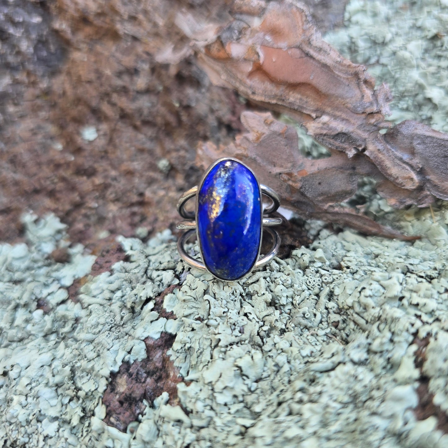 Sterling silver and lapis lazuli ring with triple shank displayed in natural setting front view.