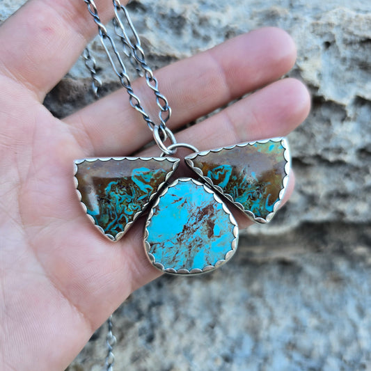 Three stone Patagonia turquoise pendant showing two triangular turquoise stones and one oval turquoise stone in mixed blue and brown hues, approximately 1.75 inches long.