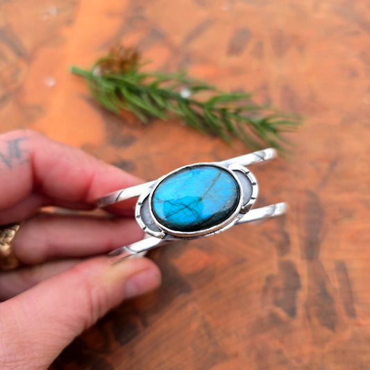 Geometric blue flash labradorite cuff bracelet in sterling silver held in hand