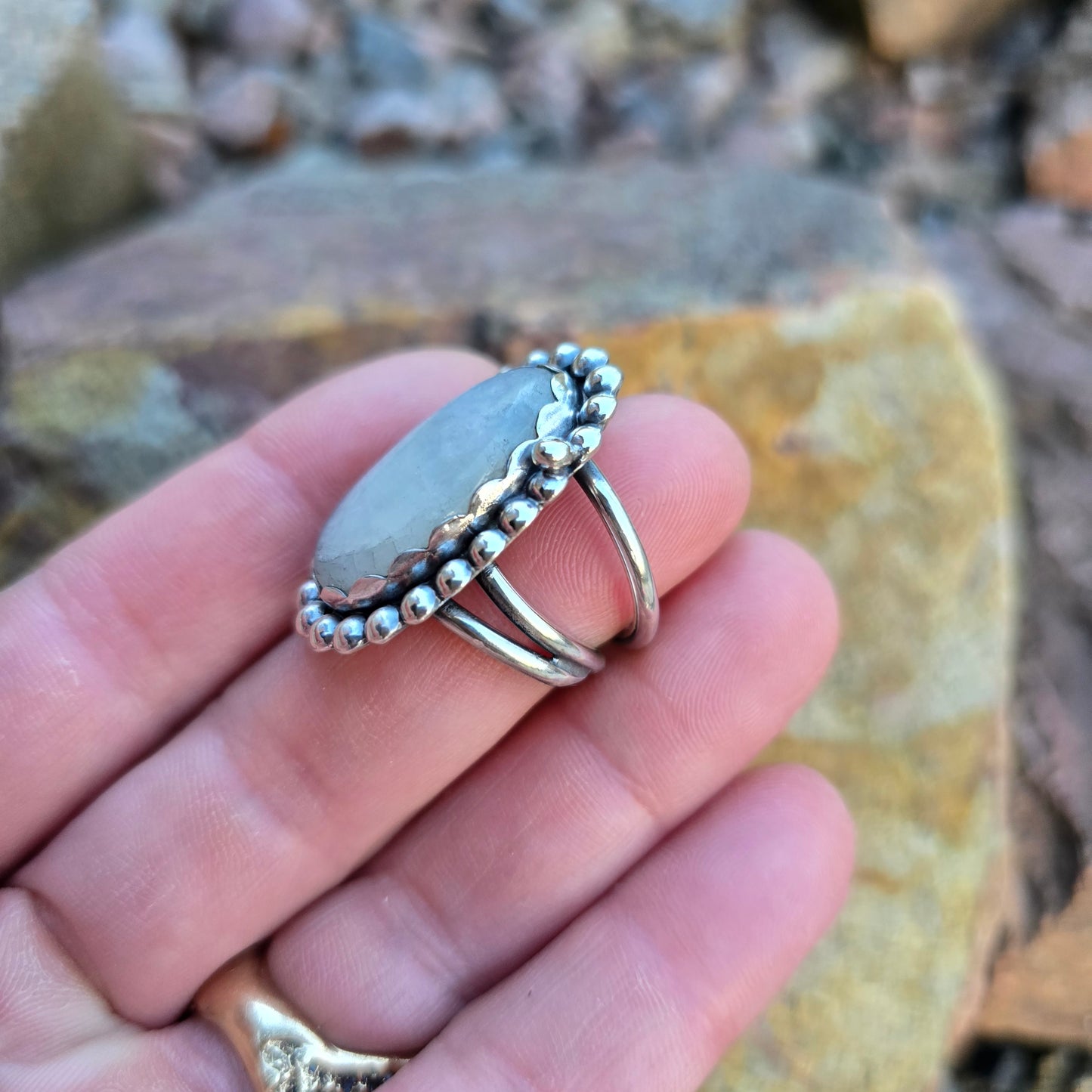 Close-up of the handcrafted rainbow moonstone ring with a bold beaded sterling silver perimeter side view