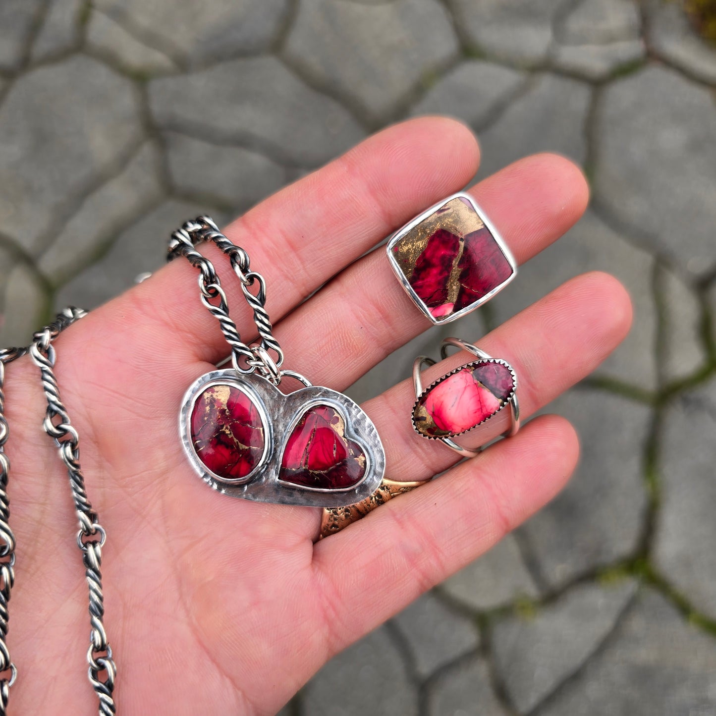 red dahlia mohave oval ring, square ring, double-stone pendant, and oxidized twisted link chain displayed together on hand