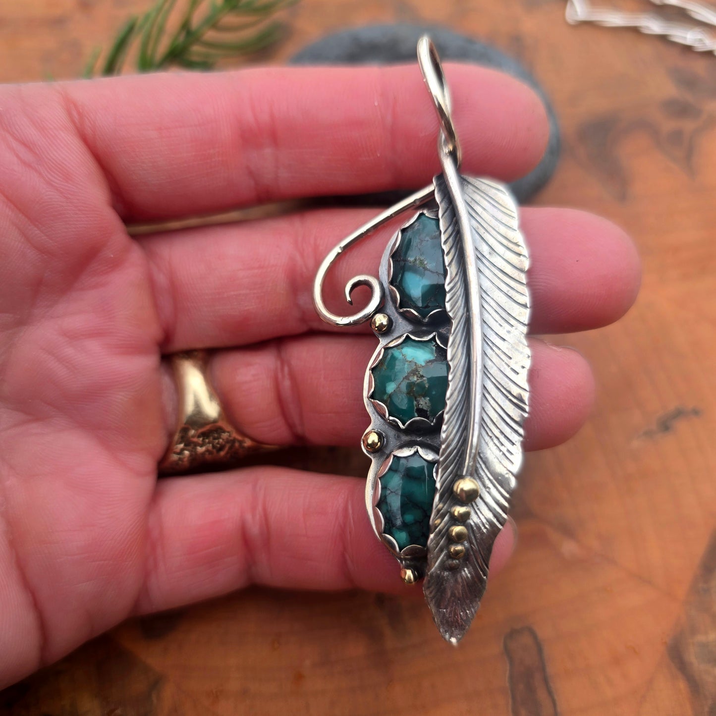 Triple turquoise long feather pendant in sterling silver on hand