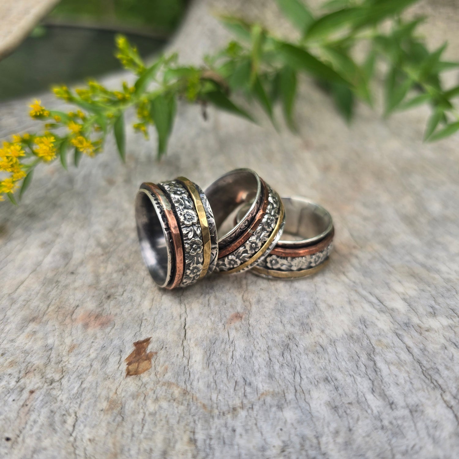 collection of blue and green rings displayed on hand near purple flowers