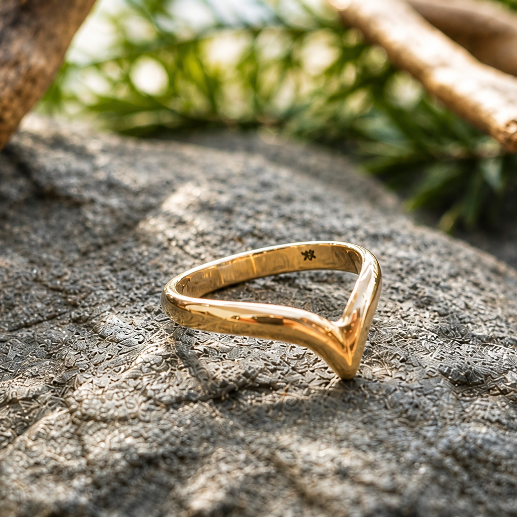 Gold ring on a textured stone surface with greenery in the background