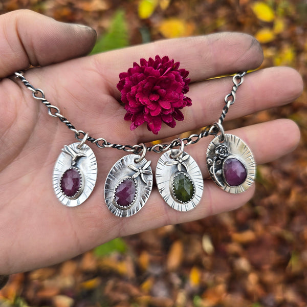 Handcrafted sterling silver pendants with ruby and peridot stones — hummingbird, dragonfly, and rose motifs created in the Sterling Roots studio.