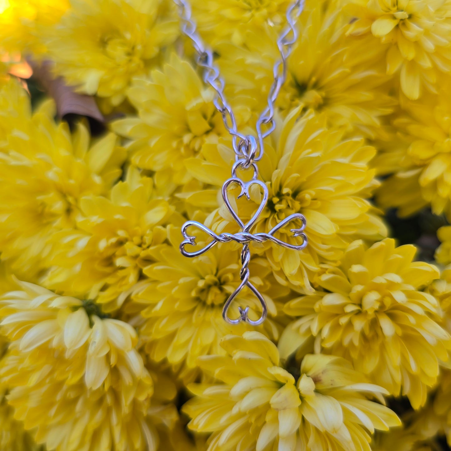 Artisan-crafted sterling silver cross and hearts pendant symbolizing strength and grace.