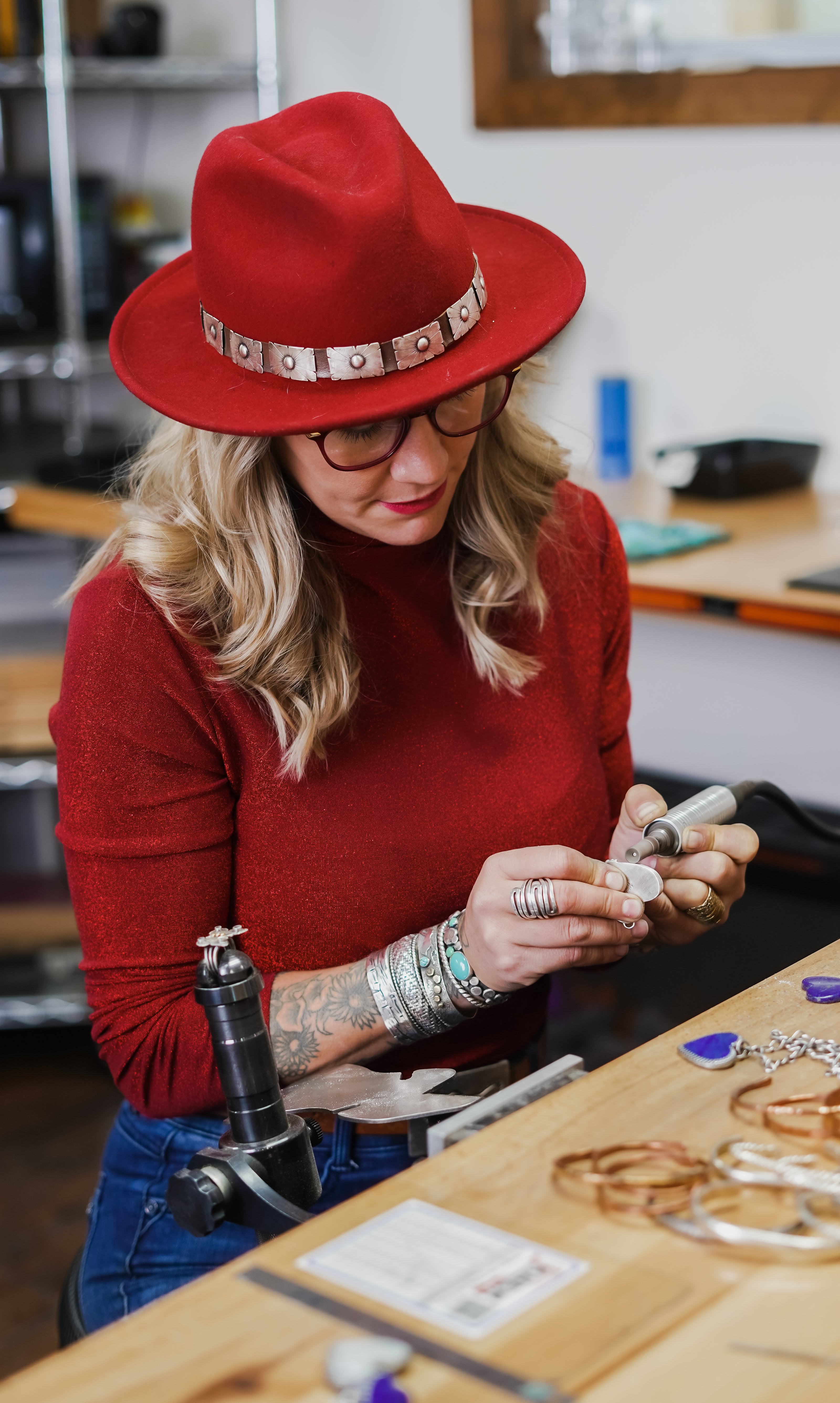 Emily Dicob, 3rd generation silversmith forging sterling silver jewelry at her workbench using traditional tools. 