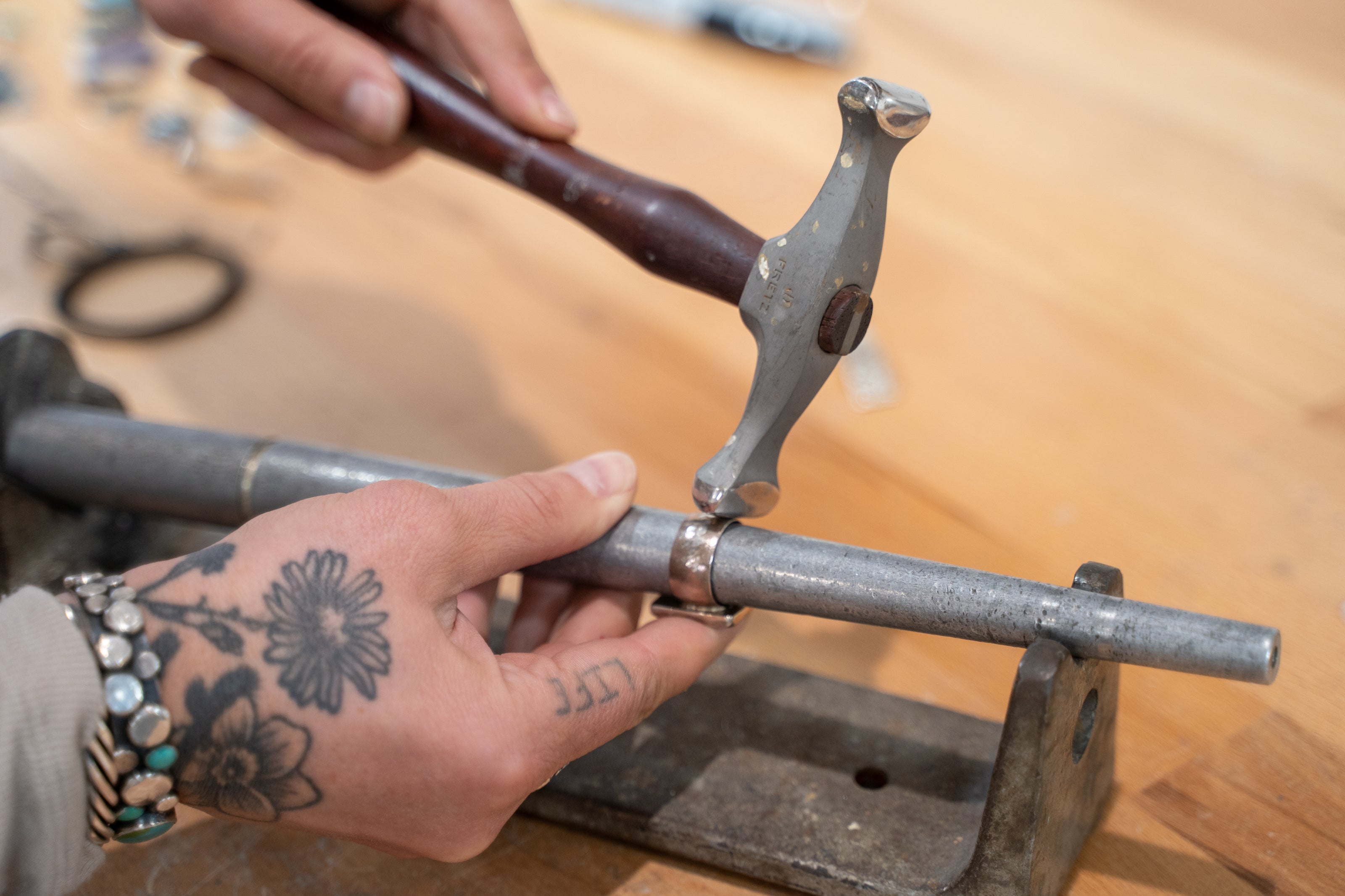 Adirondack Silversmith forging sterling silver ring with hammer and ring mandrel in studio.