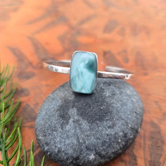 Aqua chalcedony cuff bracelet with a rectangular stone set in a streamlined sterling silver bezel, single open cuff design with visible hammer marks angled top view.