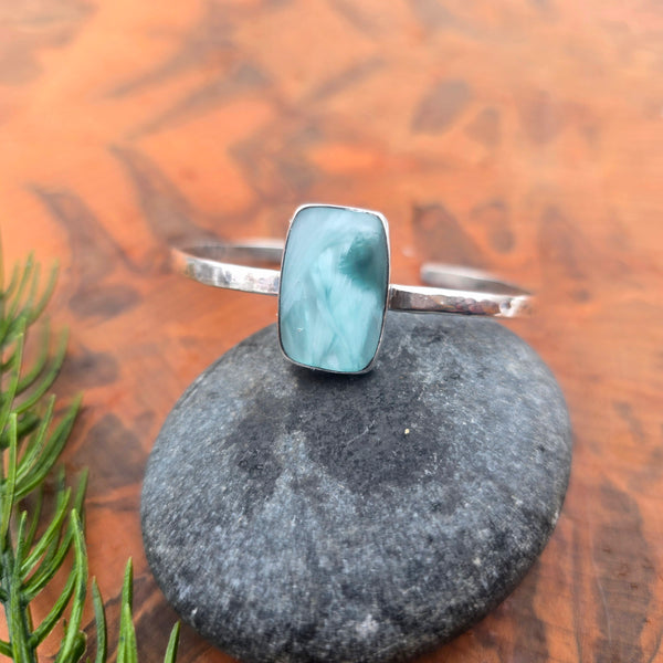 Aqua chalcedony cuff bracelet with a rectangular stone set in a streamlined sterling silver bezel, single open cuff design with visible hammer marks angled top view.