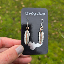Load image into Gallery viewer, Hand-forged mixed-metal feather earrings displayed on a jewelry card, featuring sterling silver feathers and copper stems.
