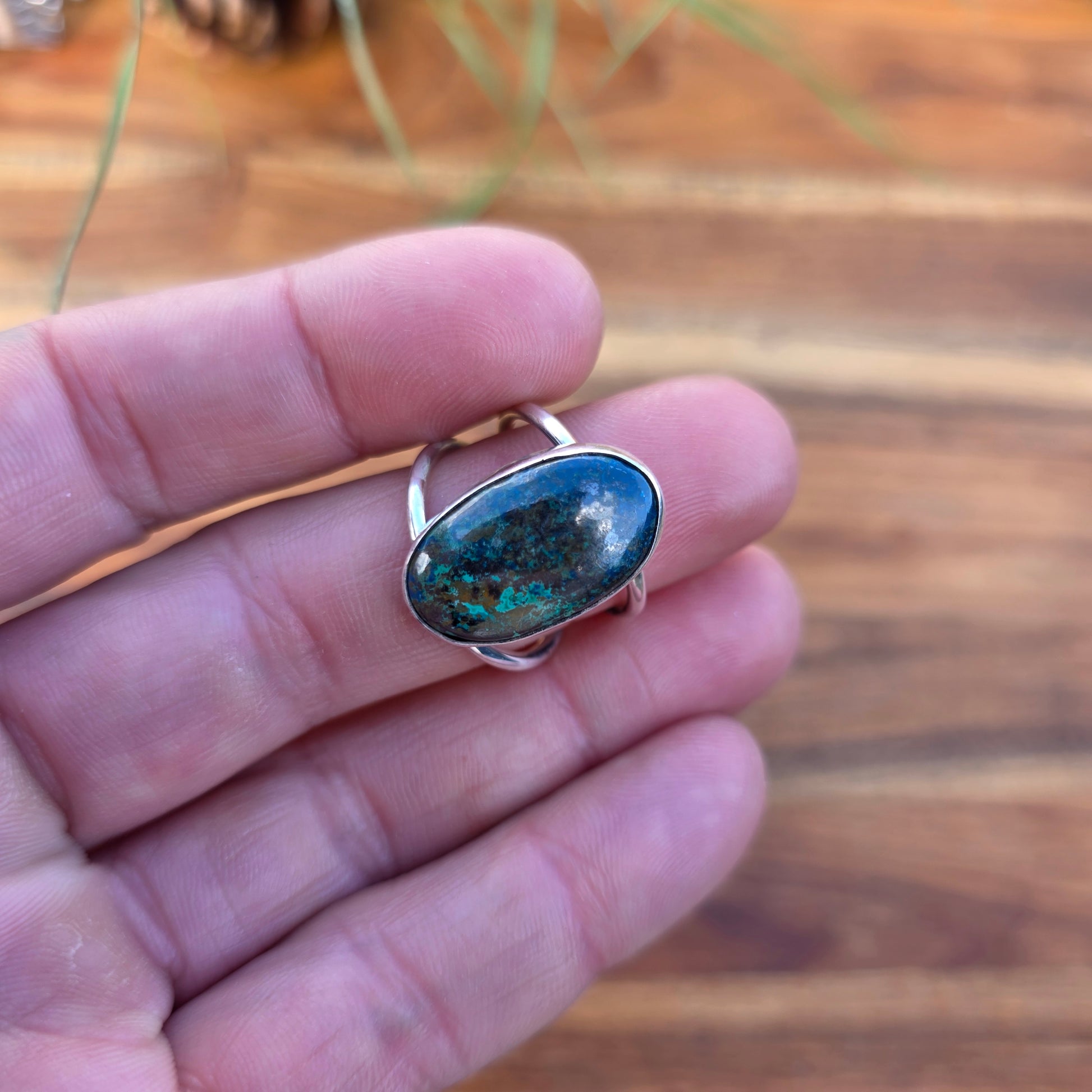 Green and blue azurite ring with a polished finish and split shank, designed with a clean, minimal form displayed on finger. 