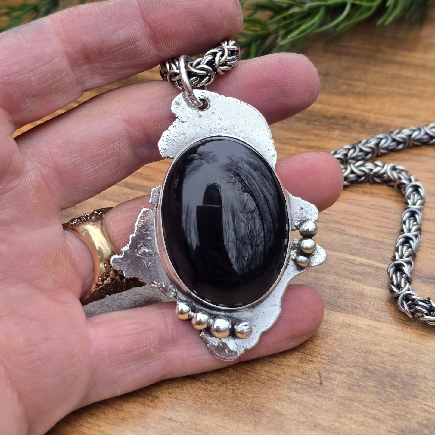 large black onyx pendant paired with sterling silver byzantine chain on hand