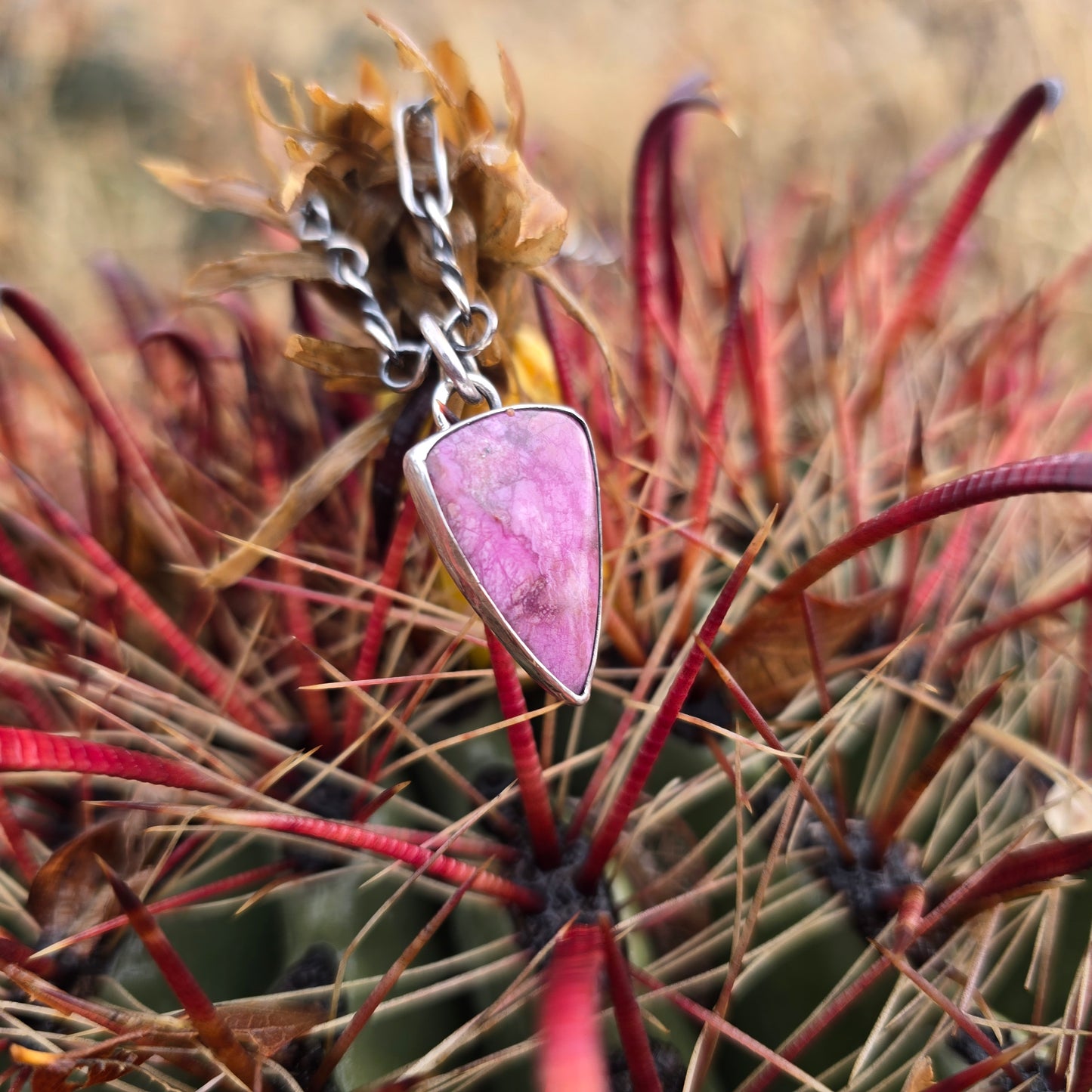 Polished pink cobalto calcite pendant in a triangular form with a smooth, reflective surface.
