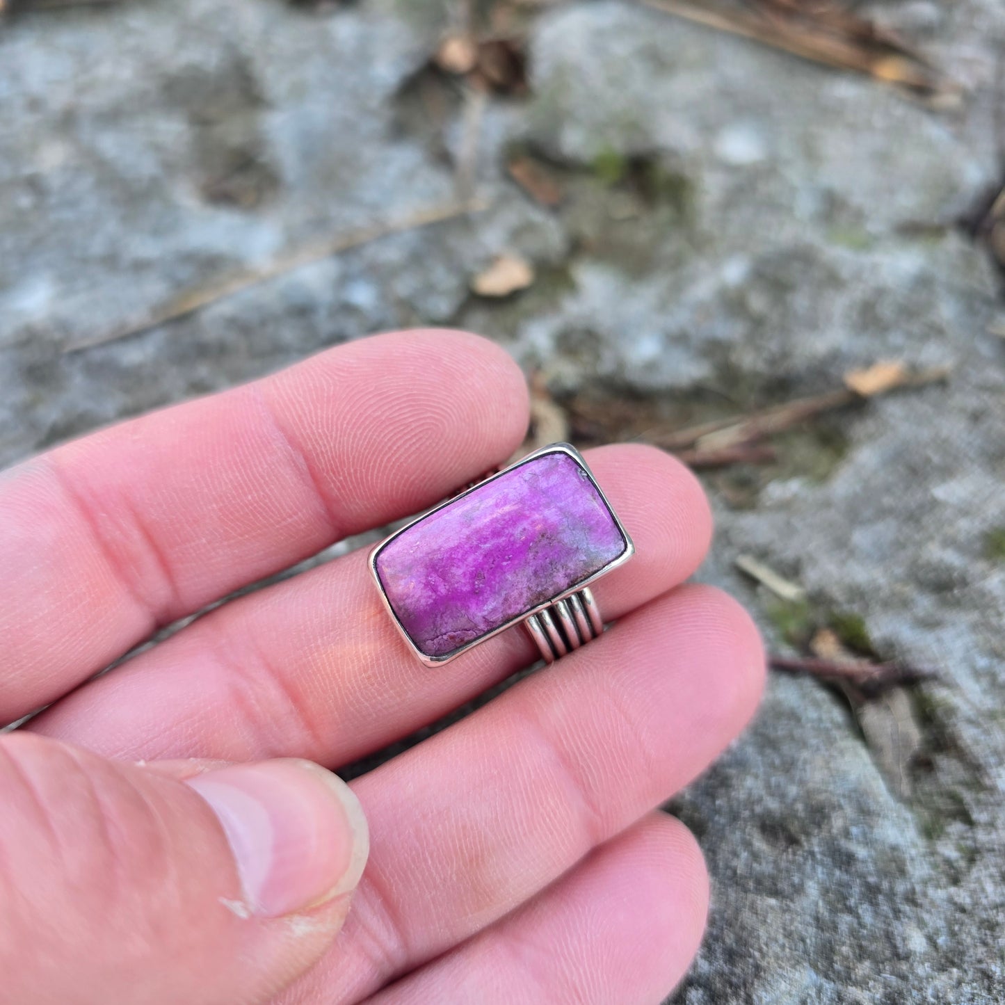 silver triple shank ring with pink stone displayed on finger