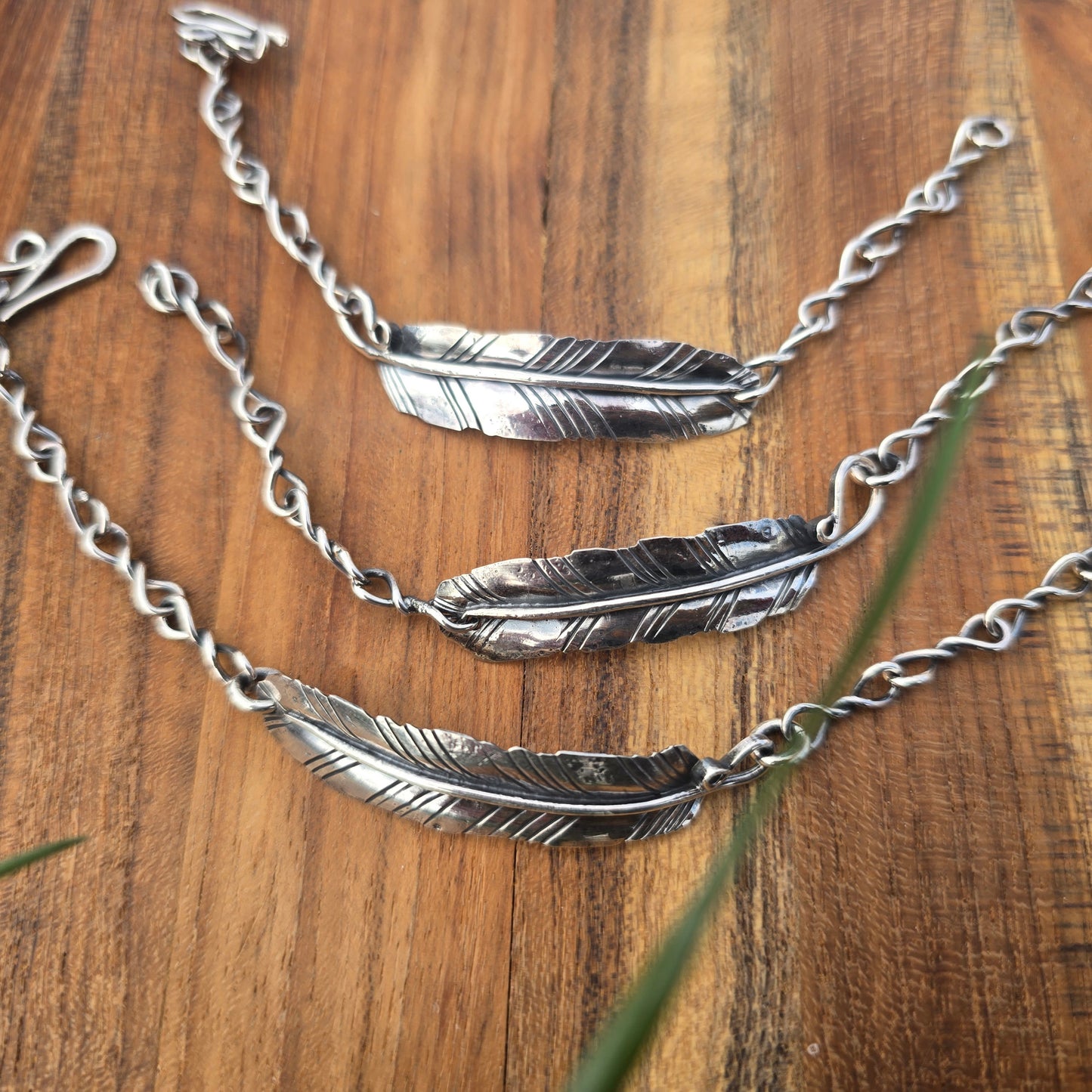 Collection of sterling silver feather bracelets on wooden surface top view