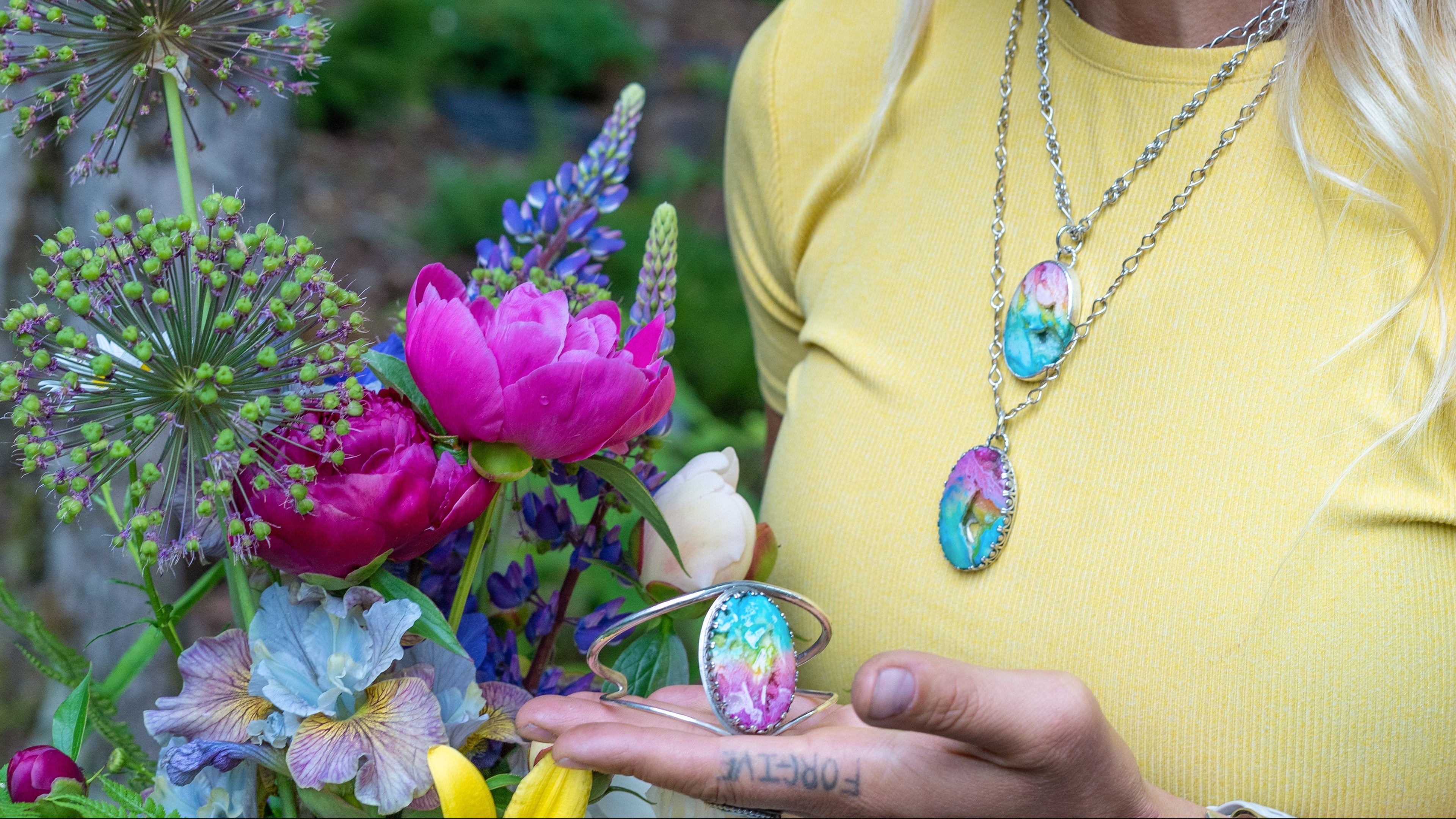 Emily Dicob of Sterling Roots wearing her hand-forged jewelry in natural setting with flowers.