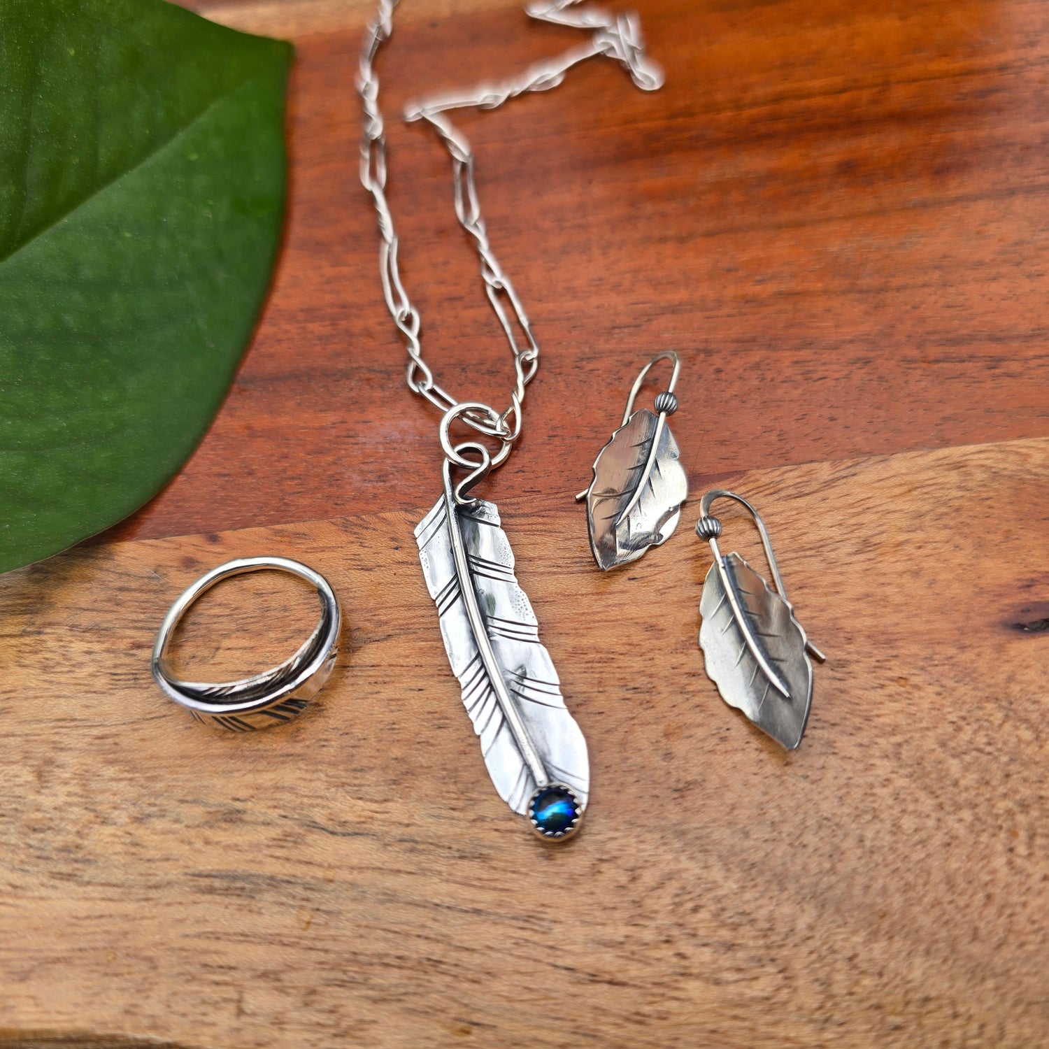 feather pendant with oil Czech glass, leaf ring, and leaf threader earrings displayed together