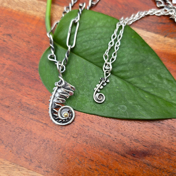 fern frond pendant with gold accent and dainty fern frond pendant displayed together on handmade chains