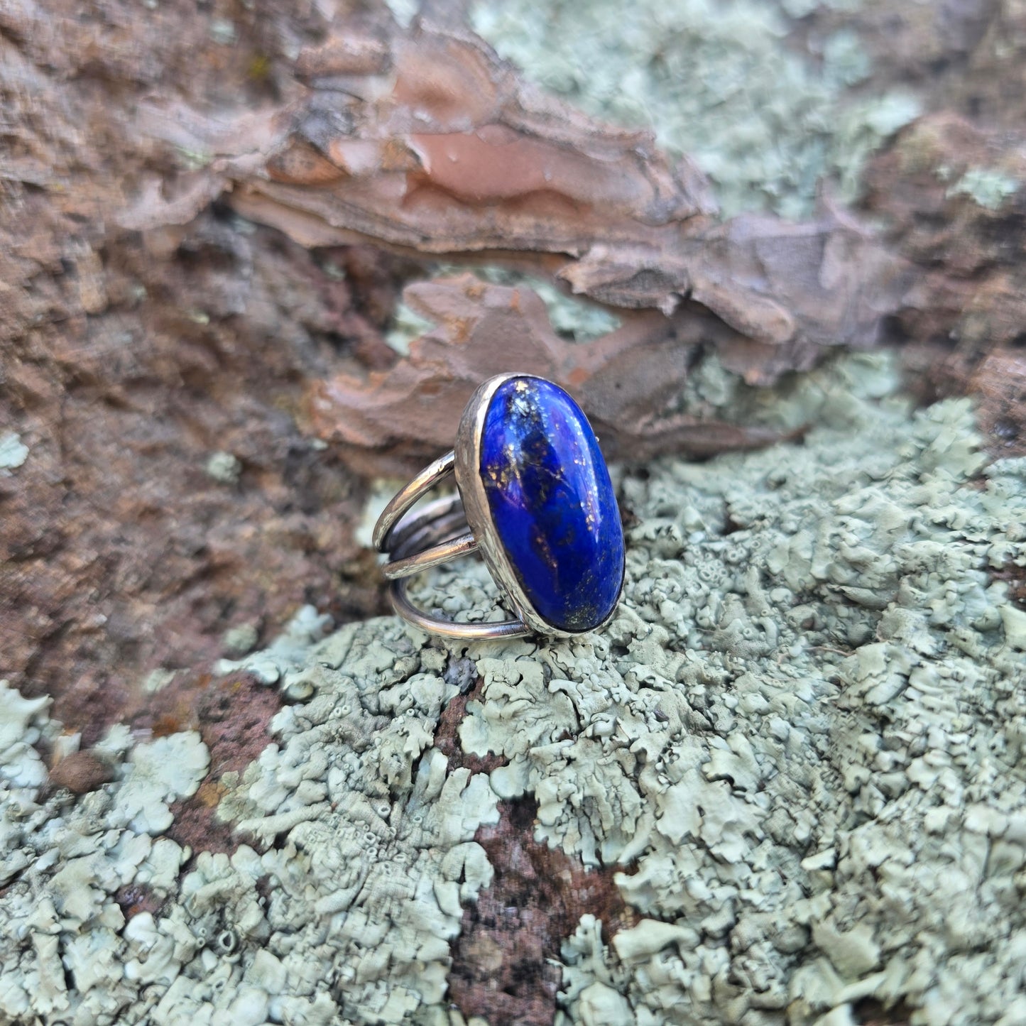 Sterling silver and lapis lazuli ring displayed in natural setting side view. 