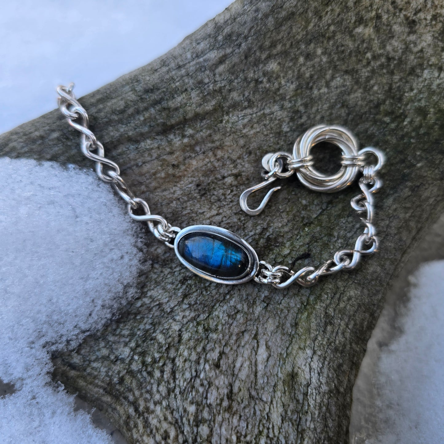 angled view of sterling silver chain bracelet with labradorite and infinity links