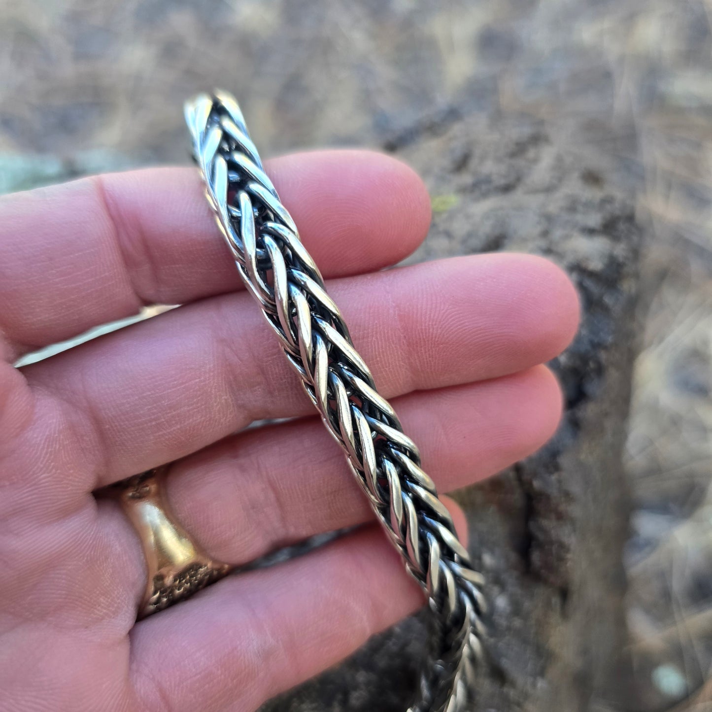 Handwoven sterling silver foxtail chain bracelet with reticulated silver end caps and a handmade clasp, built one piece at a time and sized for a 7.5–8 inch wrist displayed on hand.