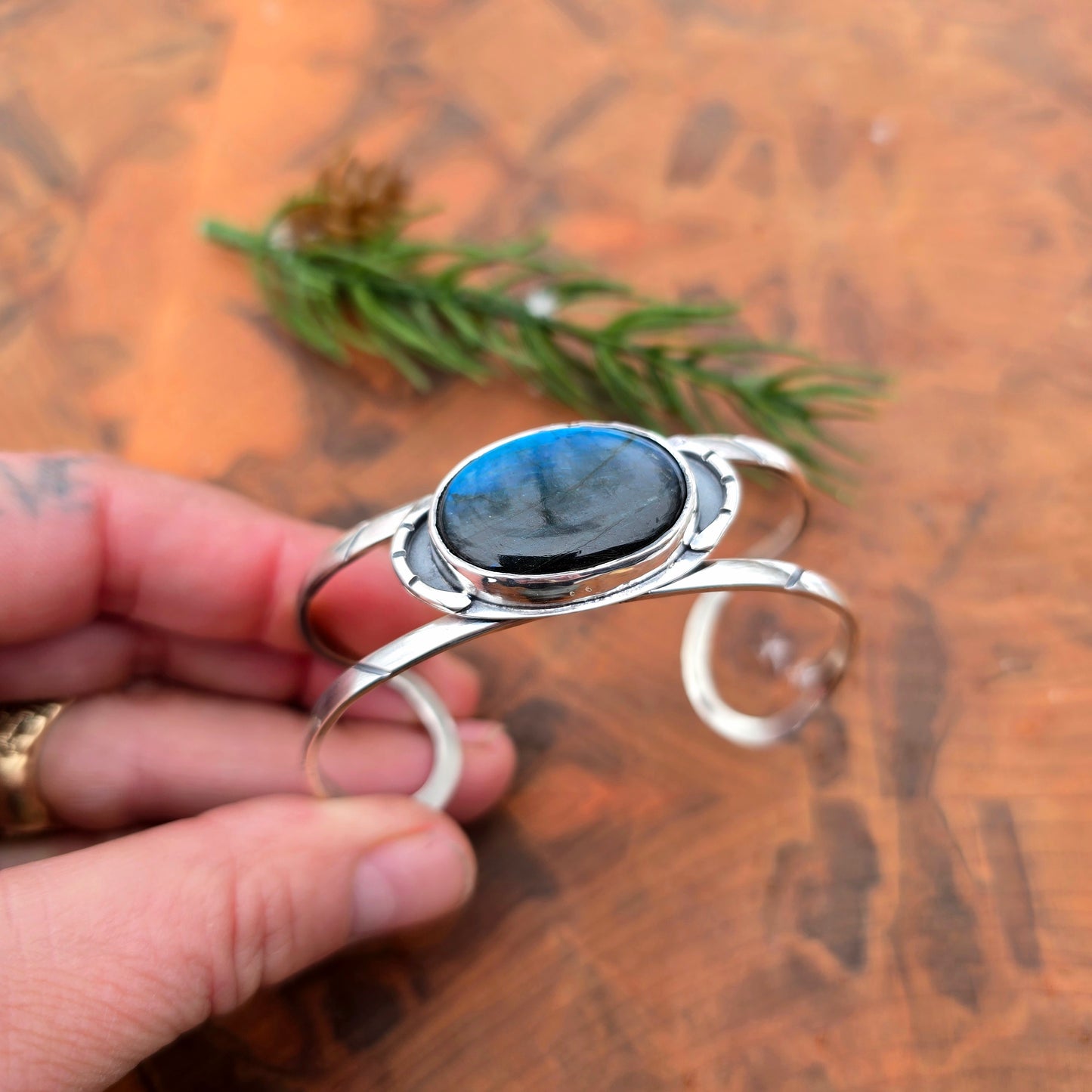 Blue flash labradorite set in geometric sterling silver cuff held in hand