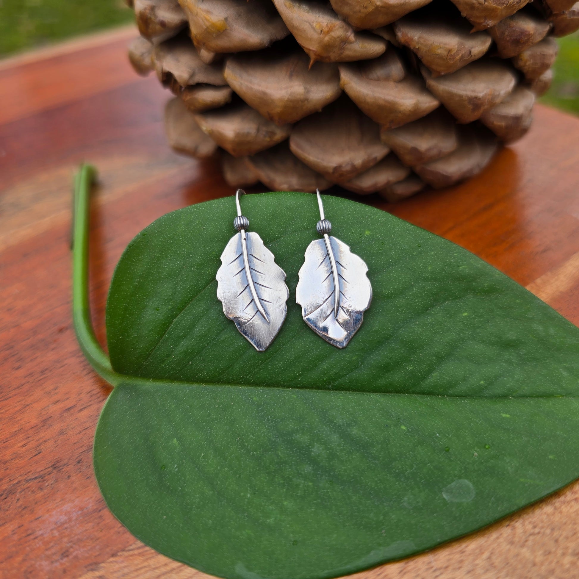 pair of sterling silver leaf threader earrings displayed on surface