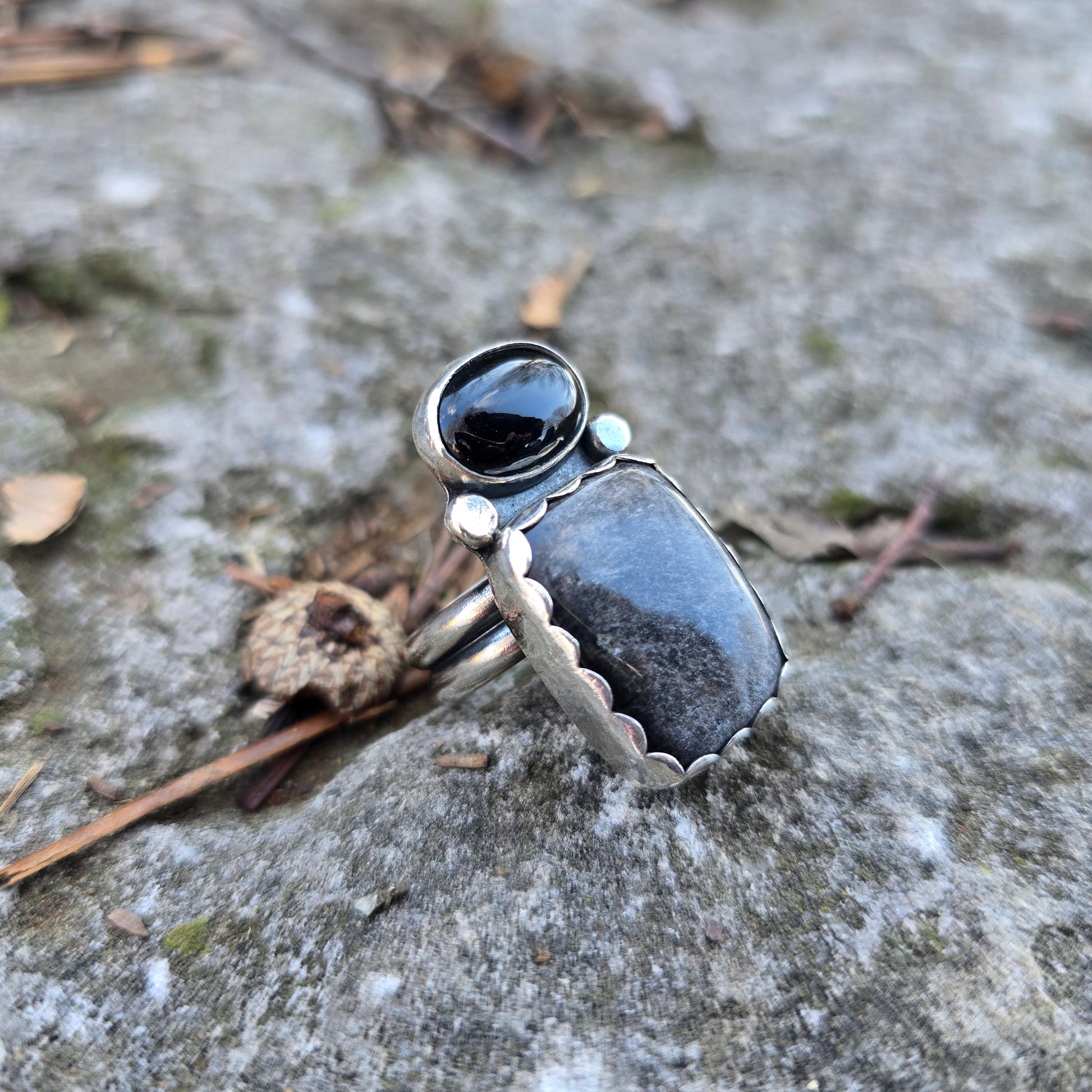 sterling silver obsidian and black onyx ring displayed on rock side angle