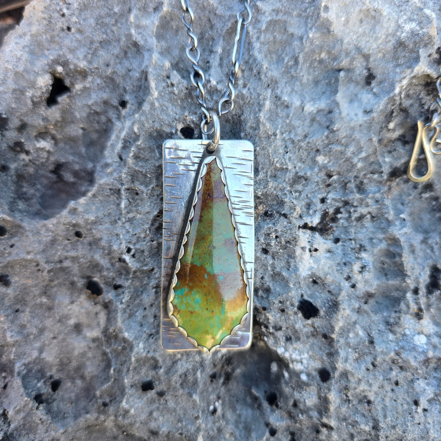 Patagonia turquoise pendant featuring green and brown matrix patterns, approximately 2.25 inches in length, photographed on a natural background.