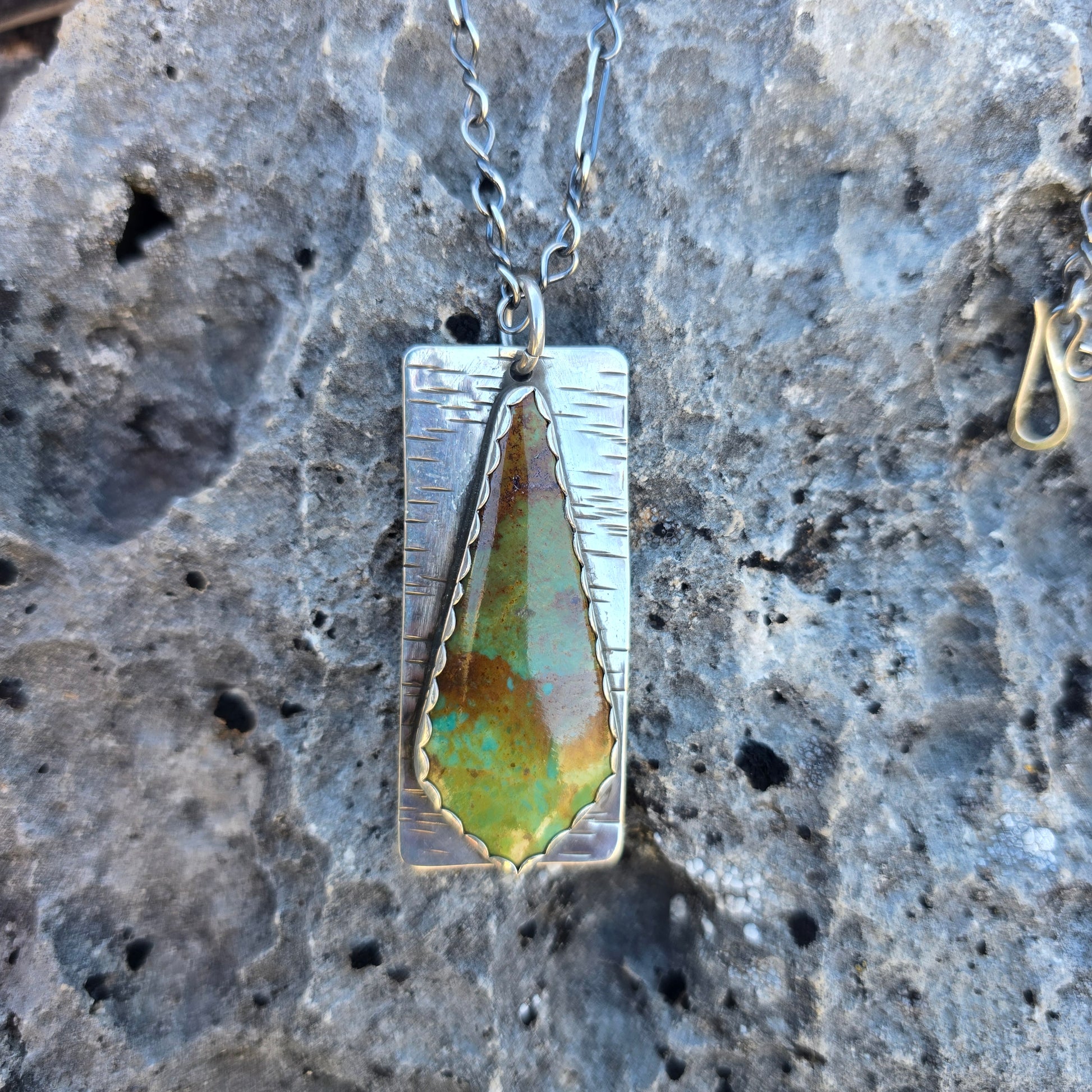 Patagonia turquoise pendant featuring green and brown matrix patterns, approximately 2.25 inches in length, photographed on a natural background.
