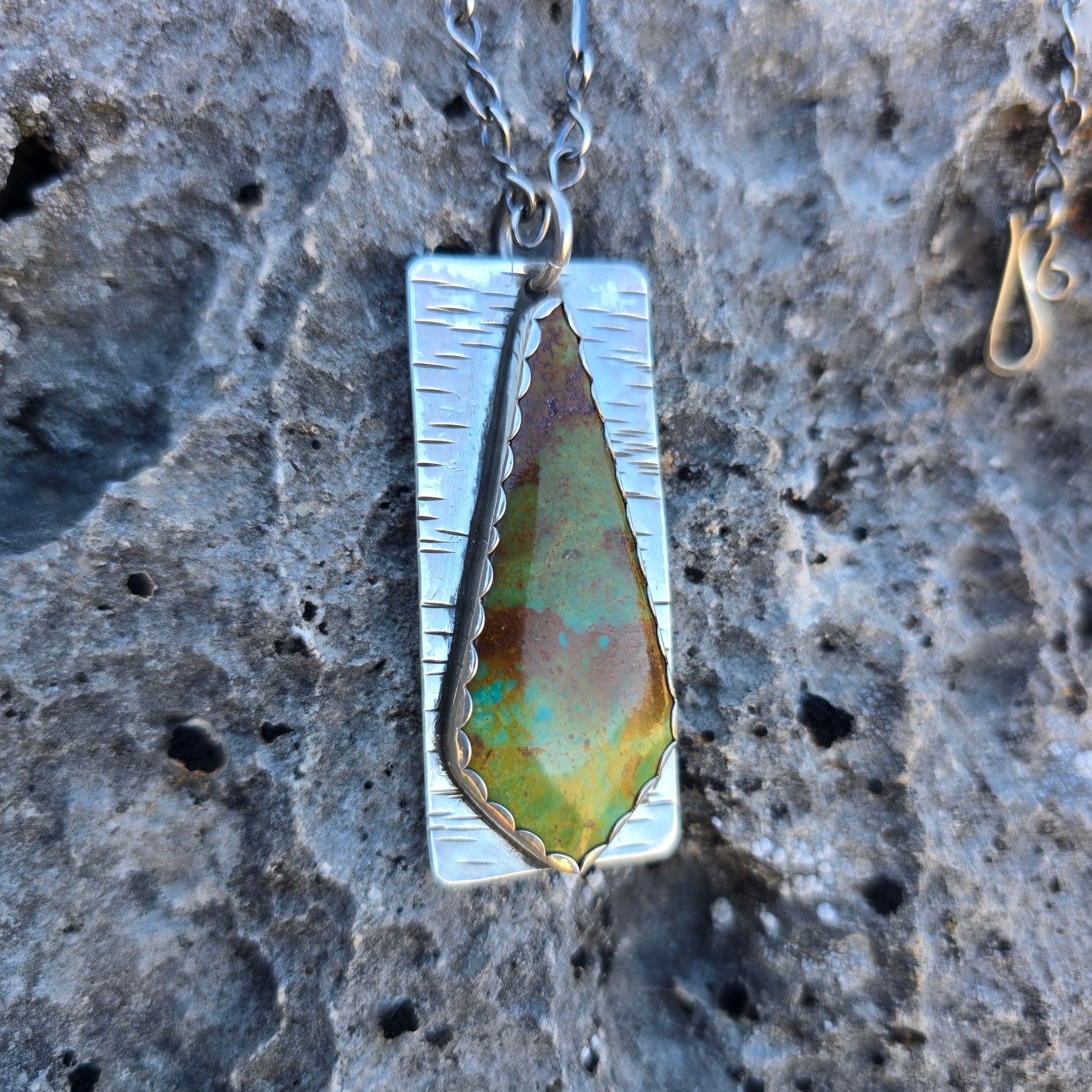 Patagonia turquoise pendant with mixed green and brown coloration, approximately 2.25 inches long, displayed on a natural background.