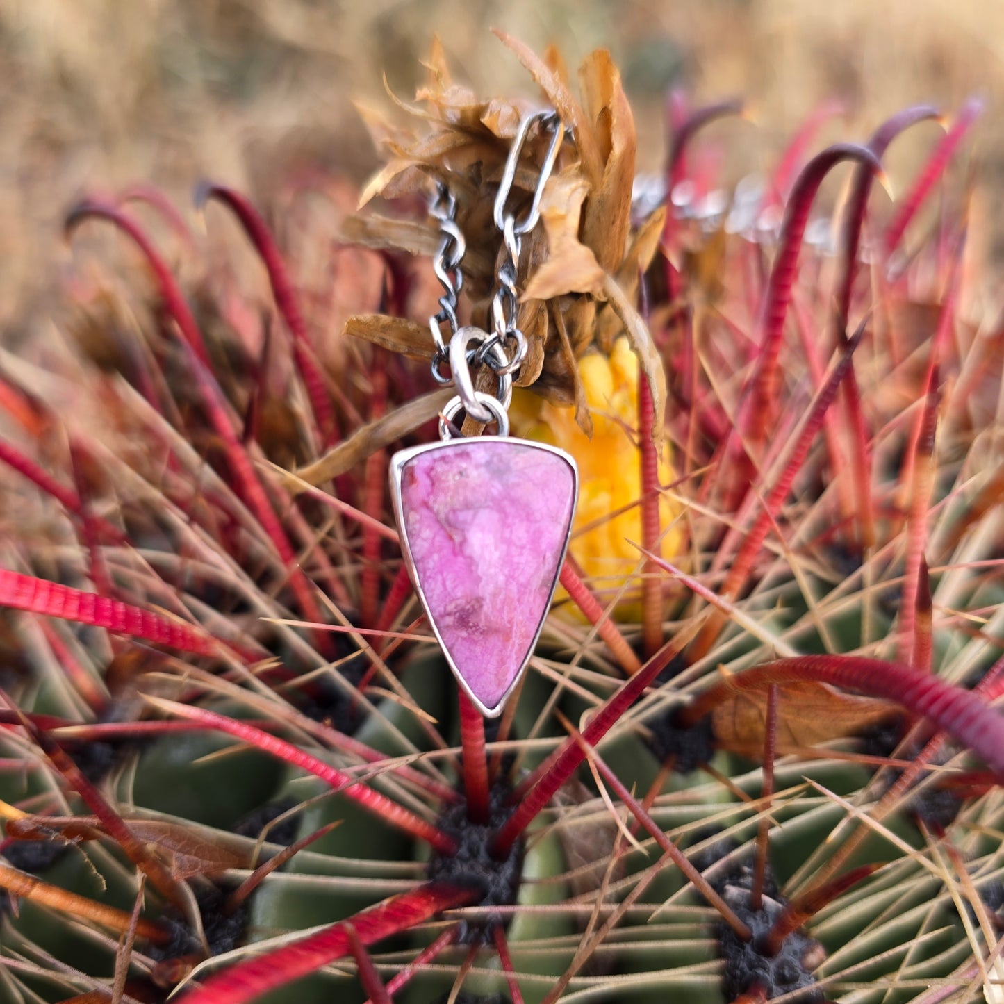 Triangular pink cobalto calcite pendant with a high-polish finish, shown in a minimal display.