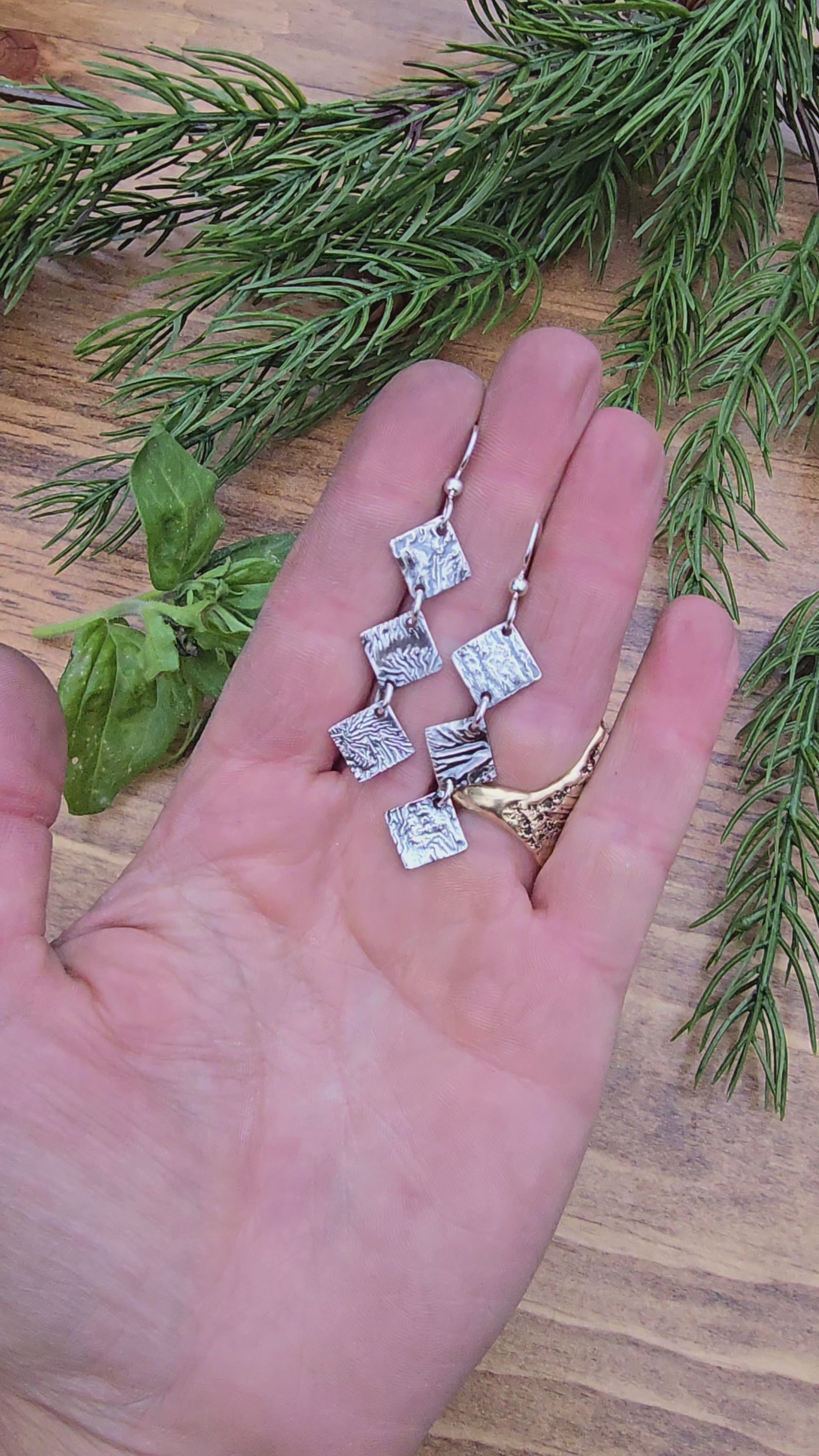 video of reticulated silver drop earrings with three diamond shapes hanging in view