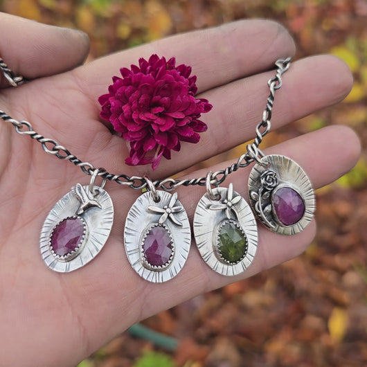 Nature-inspired pendant collection by Sterling Roots — sterling silver designs with ruby and peridot gemstones, hand-forged using traditional tools.
