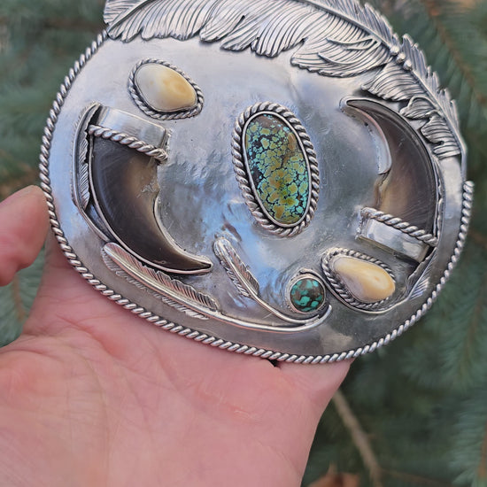 sterling silver belt buckle with turquoise centerpiece, elk ivory accents, feather and bear claw design full view