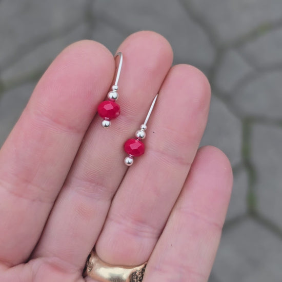 faceted red agate and sterling earrings rotated on a hand