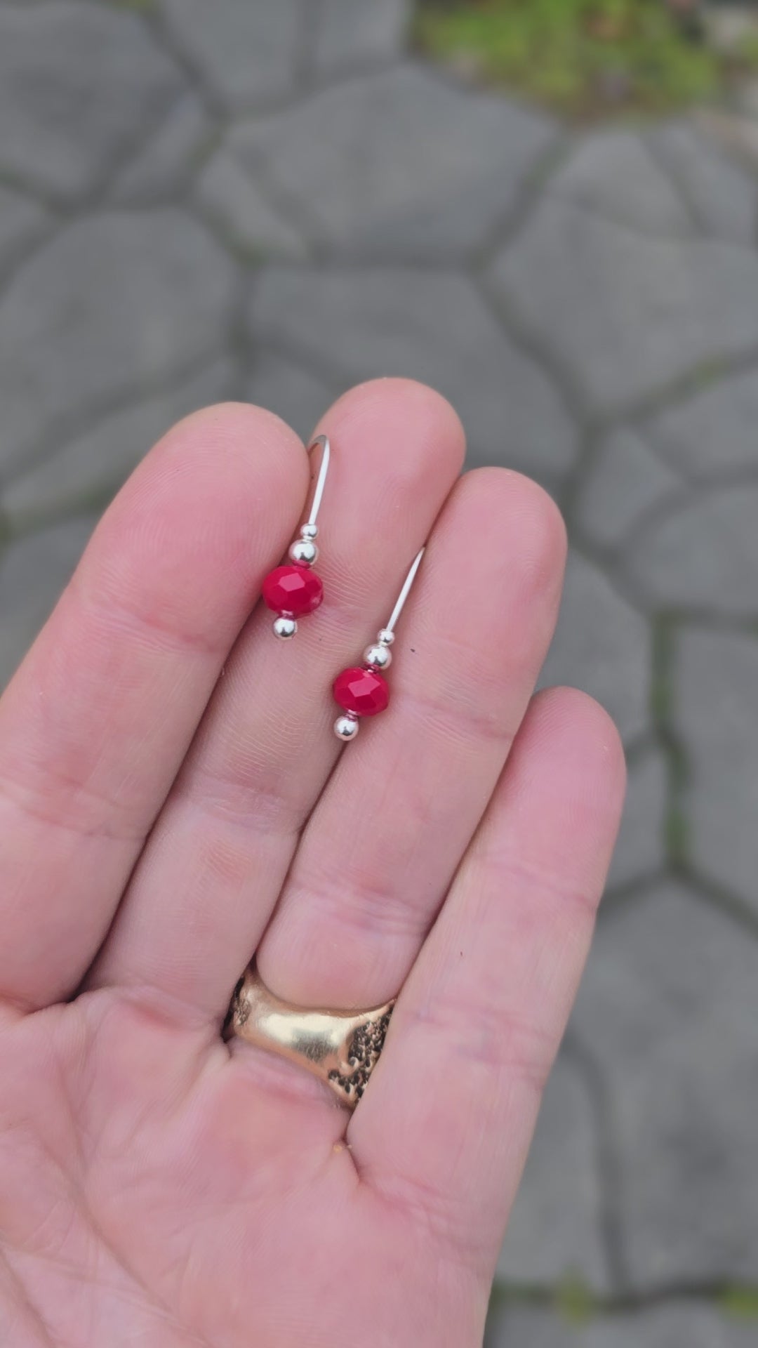 faceted red agate and sterling earrings rotated on a hand