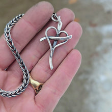Load and play video in Gallery viewer, Sterling silver cross with an intertwined heart at the center, attached to a metal key ring, shown on rotating hand
