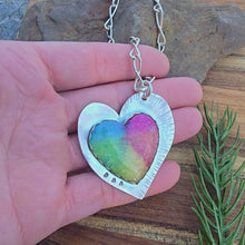 Load and play video in Gallery viewer, Top view of a heart-shaped sterling silver rainbow quartz pendant showing on hand rotating
