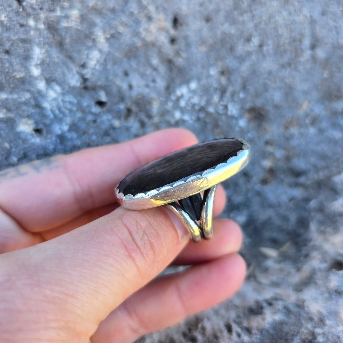 Psilomelane ring featuring a large oval stone slightly over 1.5 inches long, secured in a scalloped silver bezel on an adjustable band side view.