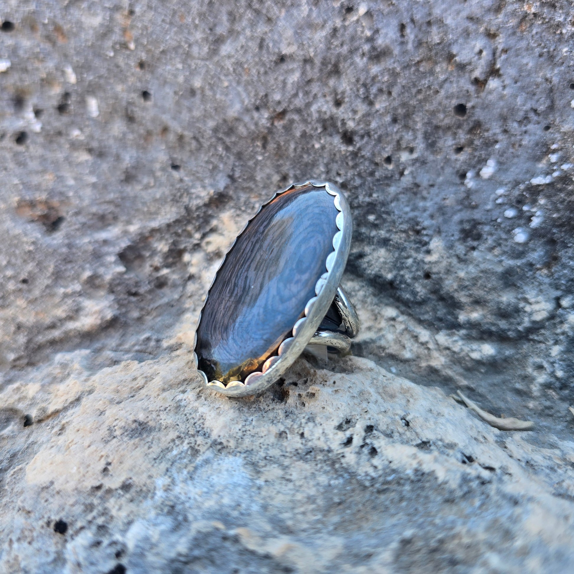 Psilomelane statement ring featuring an oval psilomelane stone just over 1.5 inches in length, set in a scalloped sterling silver bezel with an open adjustable band angled view.