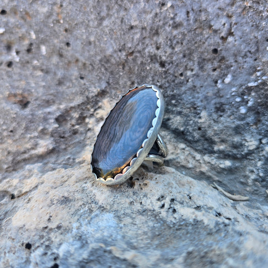 Psilomelane statement ring featuring an oval psilomelane stone just over 1.5 inches in length, set in a scalloped sterling silver bezel with an open adjustable band angled view.