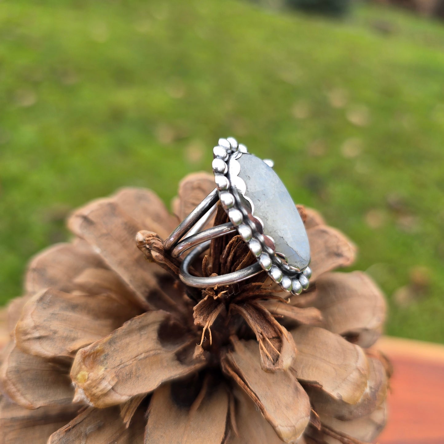 Close-up of the handcrafted rainbow moonstone ring with a bold beaded sterling silver perimeter side view