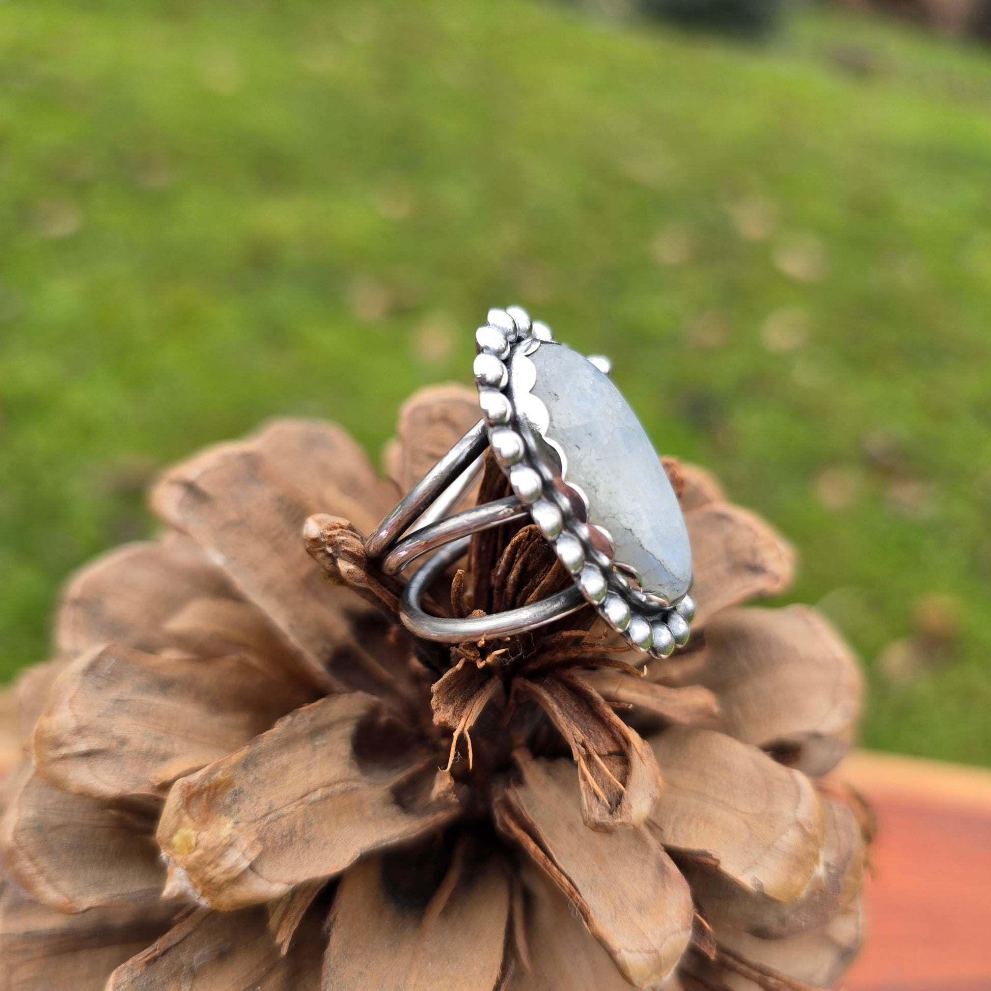 Close-up of the handcrafted rainbow moonstone ring with a bold beaded sterling silver perimeter side view