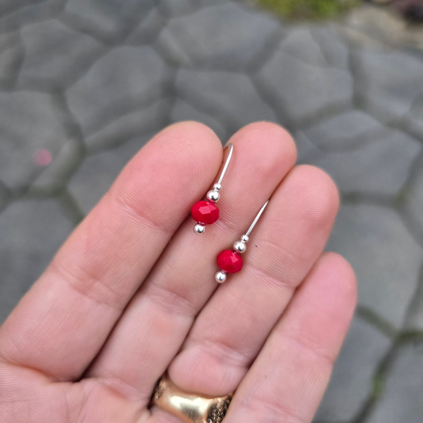 handmade red agate holiday earrings displayed on hand