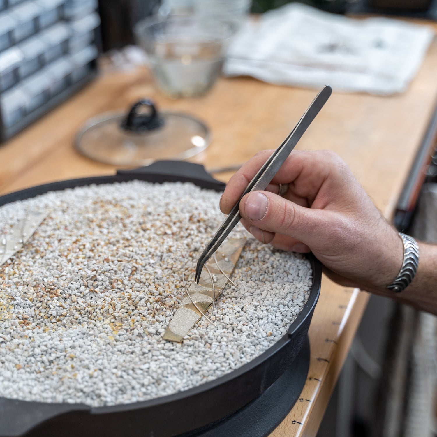 Detailed view of silversmith at Sterling Roots Studio place agentium in place before fusing with torch.