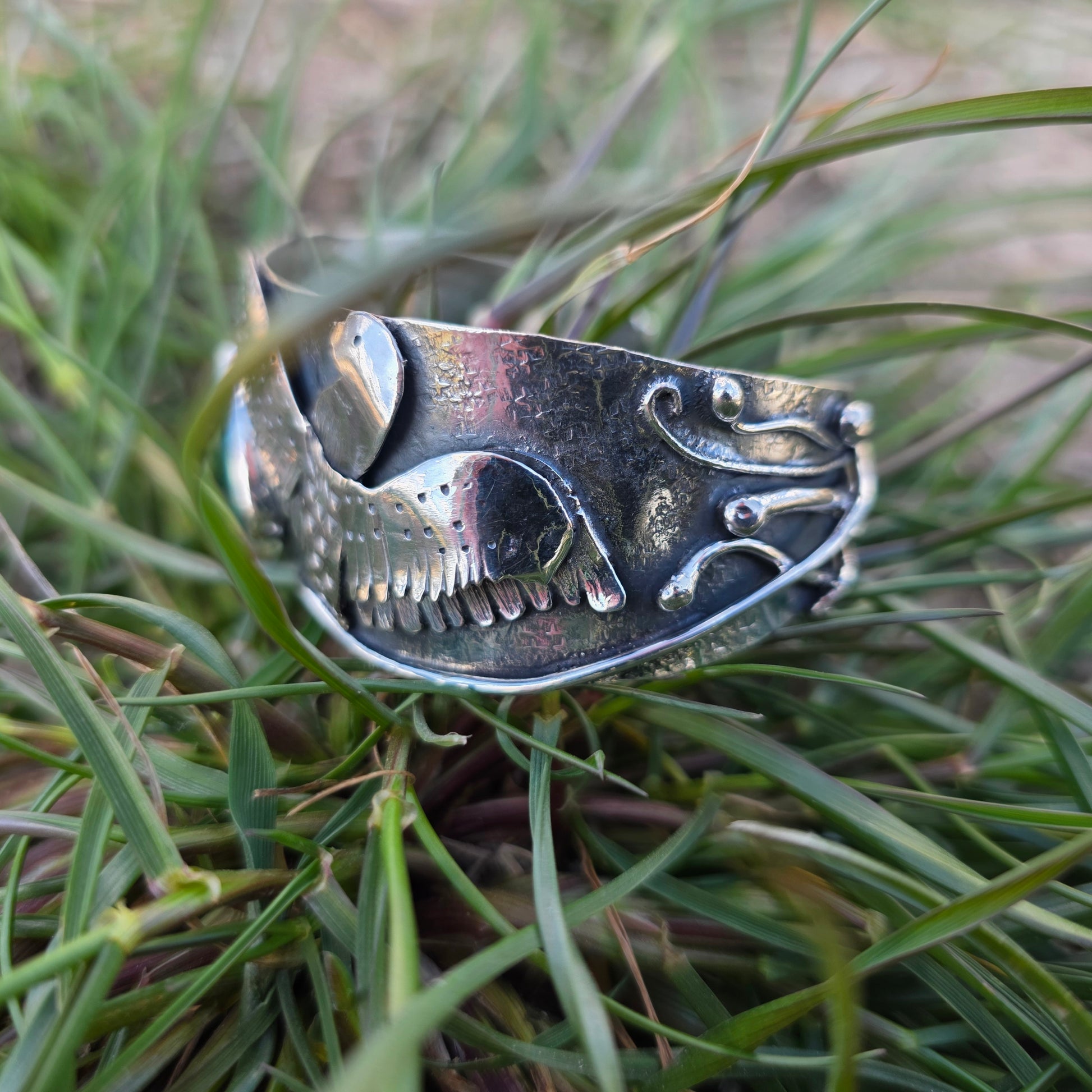 Sterling silver loon bracelet side view displayed in grass