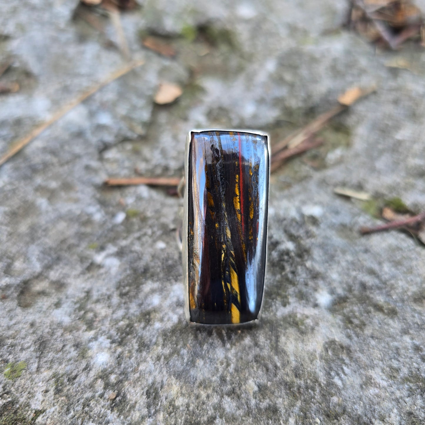 brown tiger iron rectangle stone ring displayed on rock